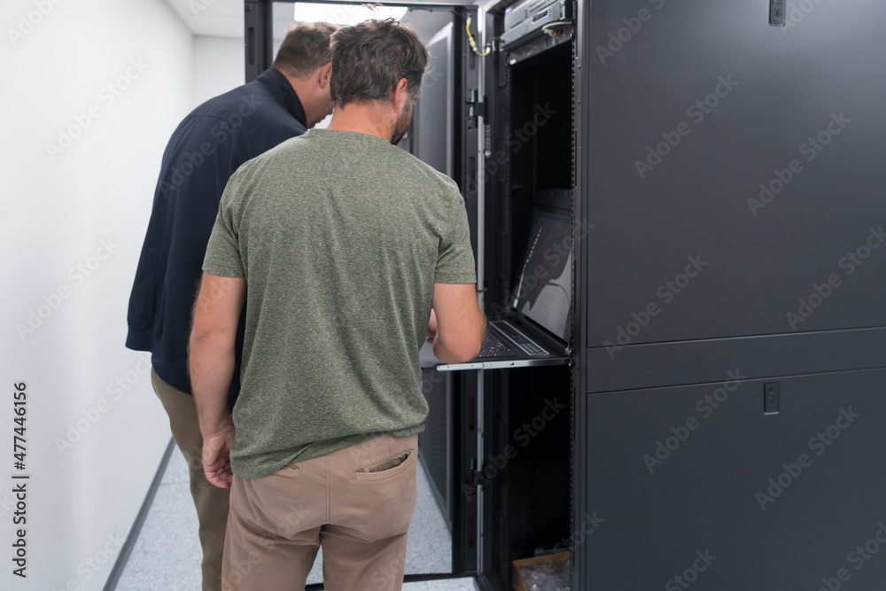  Technicians team updating hardware inspecting system performance in super computer server room or cryptocurrency mining farm.