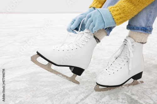 Woman lacing figure skates on ice rink, closeup