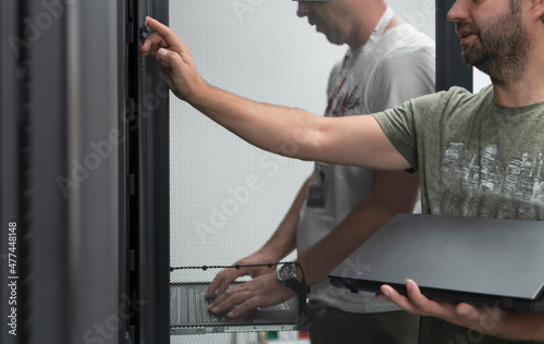  Technicians team updating hardware inspecting system performance in super computer server room or cryptocurrency mining farm.