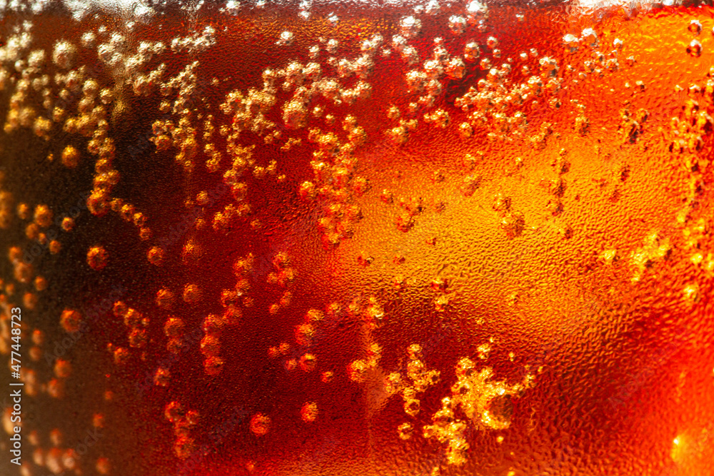 macro cola,Detail of Cold Bubbly Carbonated Soft Drink with Ice,Close up view of the ice cubes in dark cola background. Texture of cooling sweet summer's drink with foam and macro bubbles on the glass