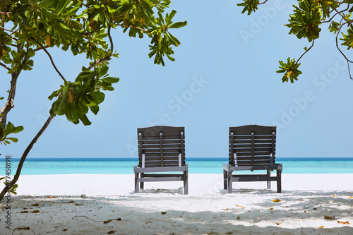 Fototapeta Naklejka Na Ścianę i Meble -  Rear view on two empty wooden deckchairs on idyllic sand beach against sea with turquoise water. .