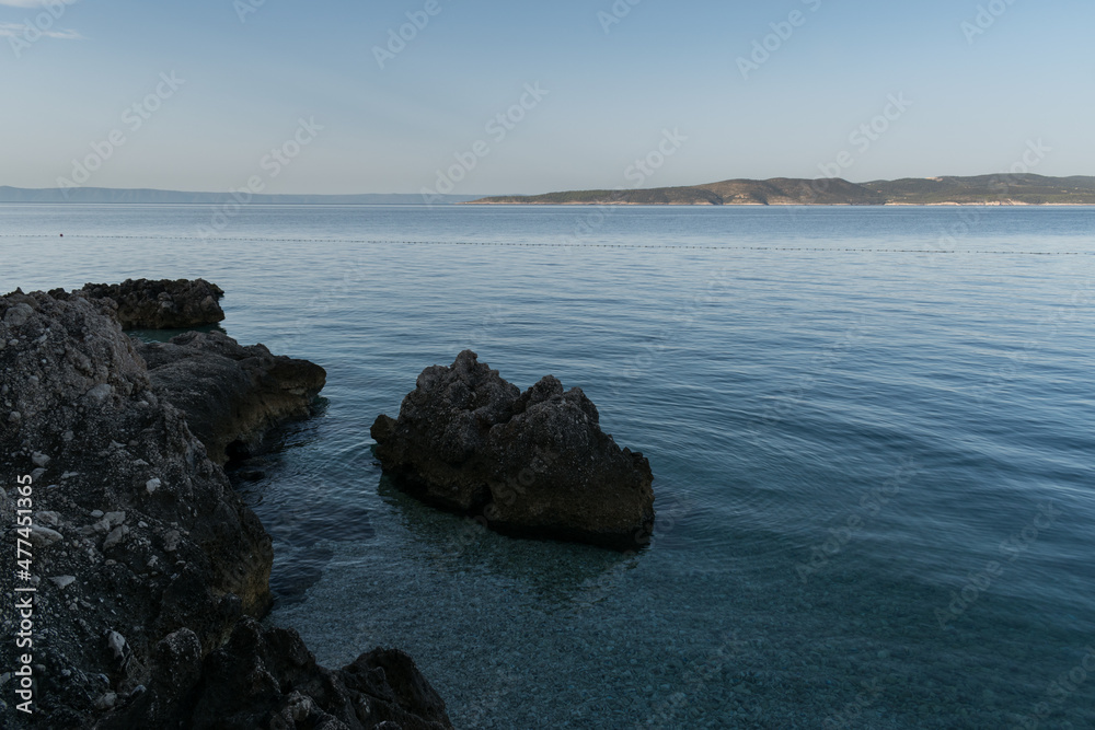 Rocky Adriatic sea shore and Brac island in distance in croatia at summer morning