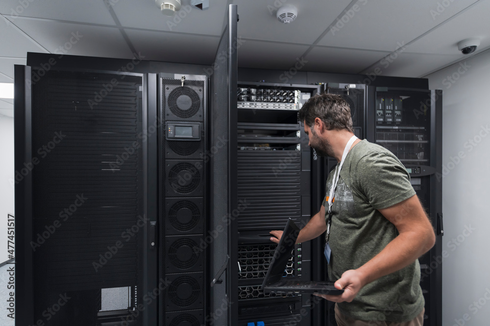 Data Center Engineer Usaing Keyboard on a Supercomputer Server Room Specialist Facility with Male System Administrator Data Center Engineer Usaing Keyboard on a Supercomputer Server Room Specialist Facility with Male System Administrator