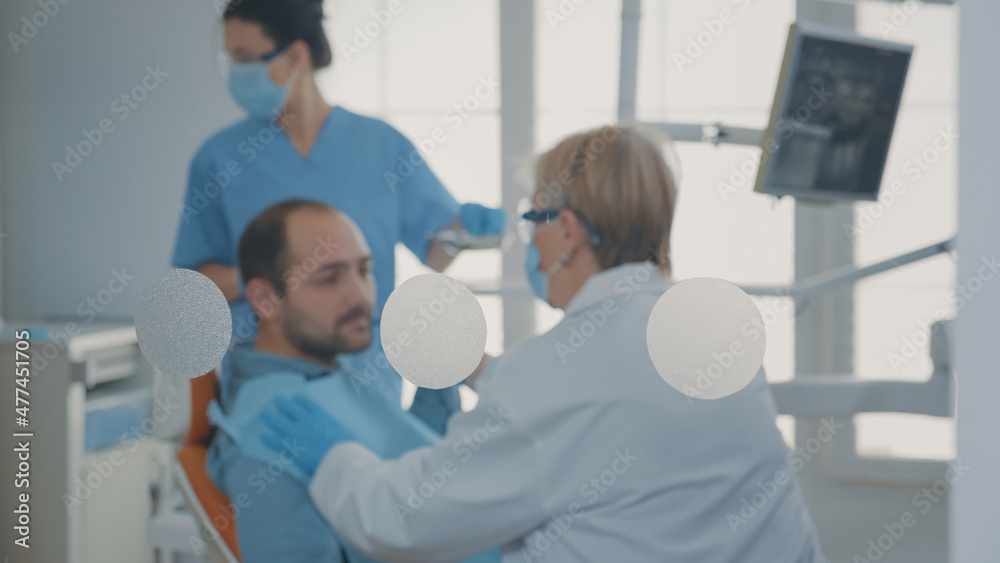 Fototapeta premium Specialist examining patient with denture problems and caries, preparing for dental surgery at oral care clinic. Dentist doing orthodontic consultation and consulting man in pain.