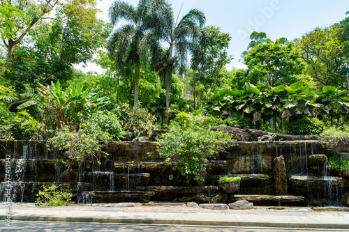 Canvas Print Water pouring off rock a feature in front of trees at the Perdana Botanical Garden, - Kuala Lumpur, Malaysia