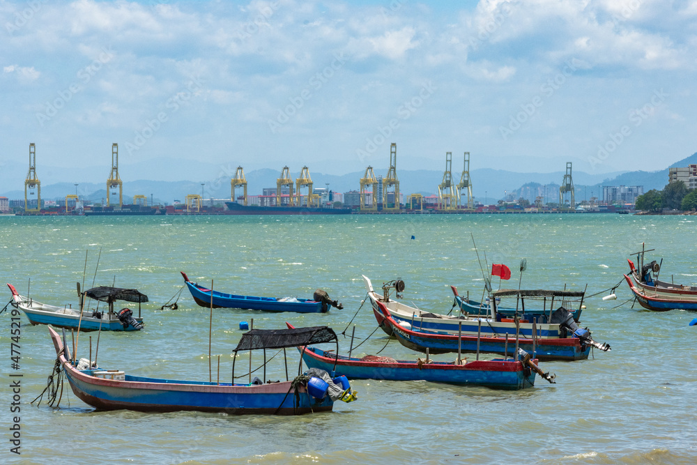 Long-Tail Boats moored off George Town with cranes at Butterworth Port in the background, Penang, Malaysia.