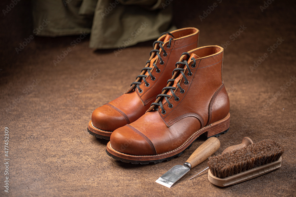 Handcrafted brown leather shoes with cobbler tools on the backgound