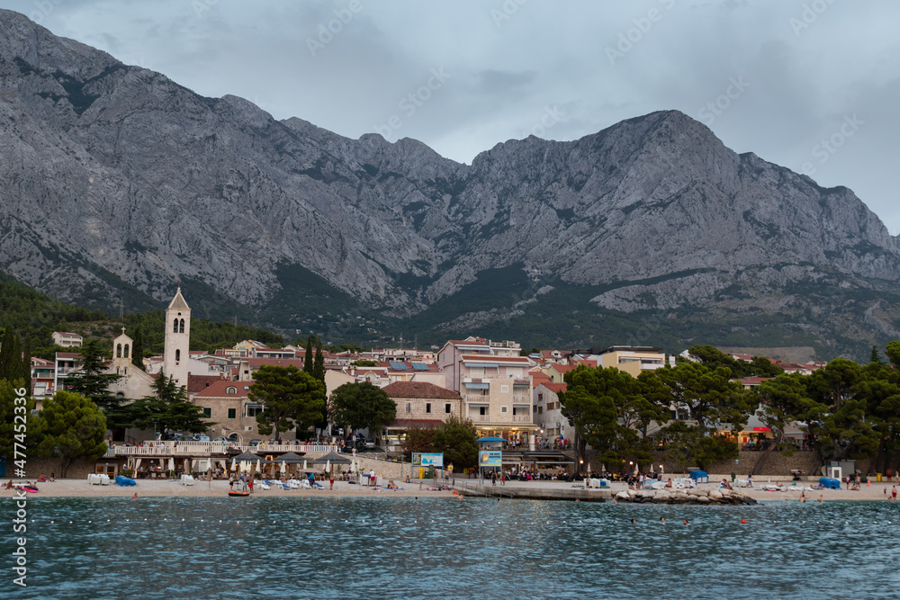 Tourist resort Baska Voda and main beach, in Croatia against mountain Biokovo at summer dusk