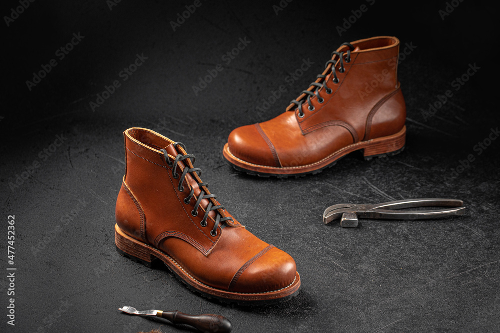Handcrafted brown leather shoes with cobbler tools on the backgound Handcrafted brown leather shoes with cobbler tools on the backgound