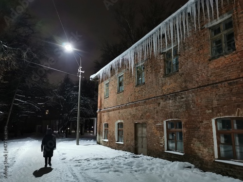 winter evening icicles hanging from the roof in the light of a lantern