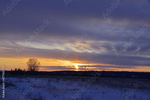 Winter sunset in the village over the forest