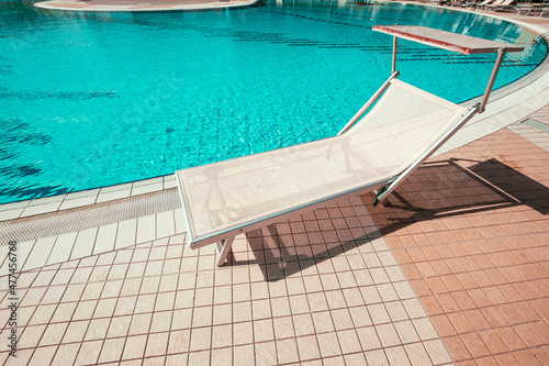 Resort pool. Summer resort chair, relax lounge at luxury hotel pool. Beach lounger chaise. Vacation sunbed. Blue water, sunny happy travel holiday.