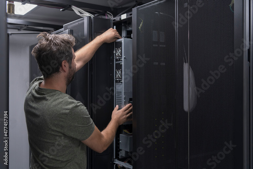 IT engineer working In the server room or data center The technician puts in a rack a new server of corporate business mainframe supercomputer or cryptocurrency mining farm. 