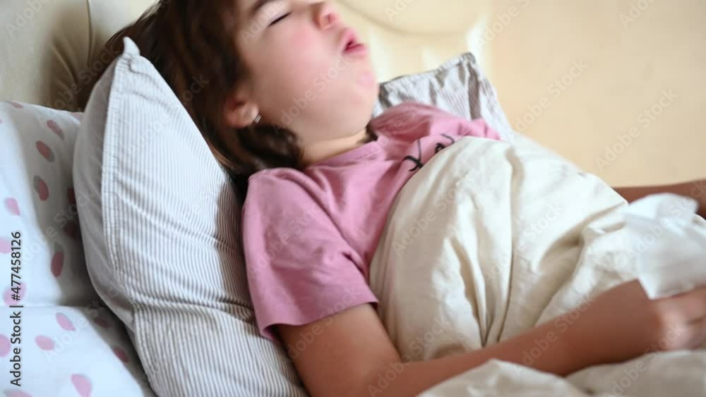 a 10-year-old girl lies in bed sick, coughs, blows her nose into a napkin. High quality 4k footage a 10-year-old girl lies in bed sick, coughs, blows her nose into a napkin. High quality 4k footage