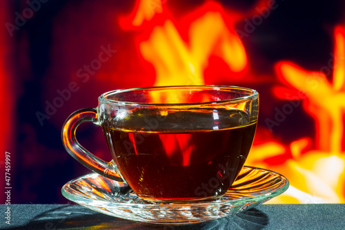 glass cup of black tea on a background of fire