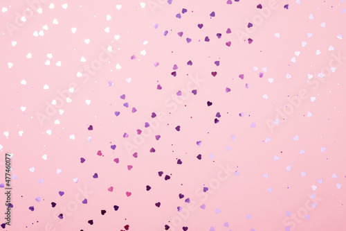 Purple glittering hearts on a pink pastel background. Festive background.