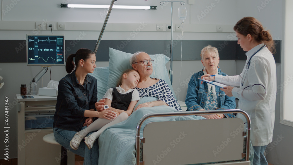 Little girl and mother visiting grandpa in hospital ward while doctor consults him for recovery. Medic explaining diagnosis to ill patient and family in visit at clinic. Physician at checkup Little girl and mother visiting grandpa in hospital ward while doctor consults him for recovery. Medic explaining diagnosis to ill patient and family in visit at clinic. Physician at checkup