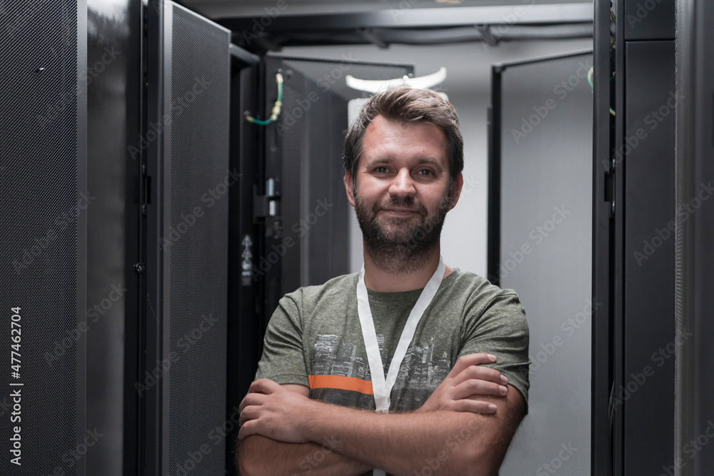 Portrait of male technician or network administrator standing brave as a hero with arms crossed in data center server room. Portrait of male technician or network administrator standing brave as a hero with arms crossed in data center server room.