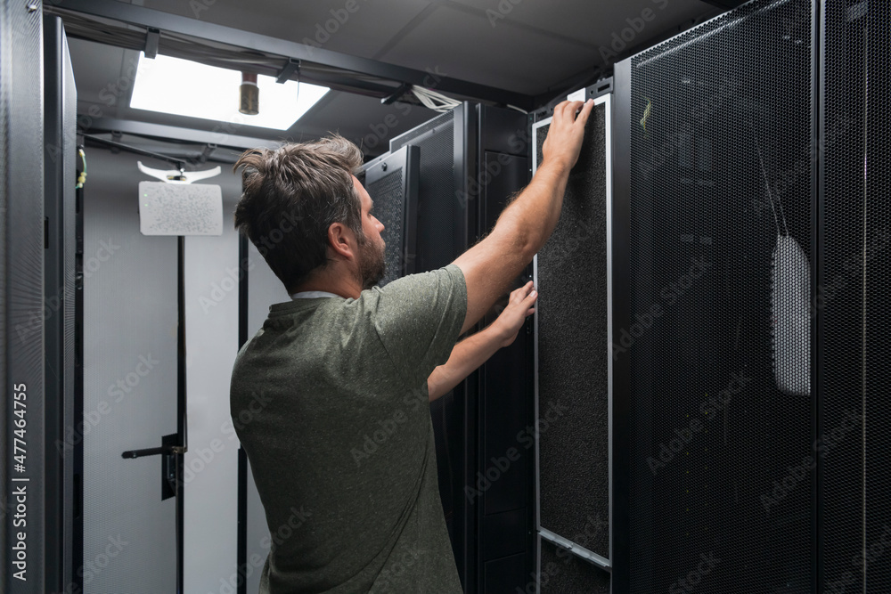 IT engineer working In the server room or data center The technician puts in a rack a new server of corporate business mainframe supercomputer or cryptocurrency mining farm. IT engineer working In the server room or data center The technician puts in a rack a new server of corporate business mainframe supercomputer or cryptocurrency mining farm.