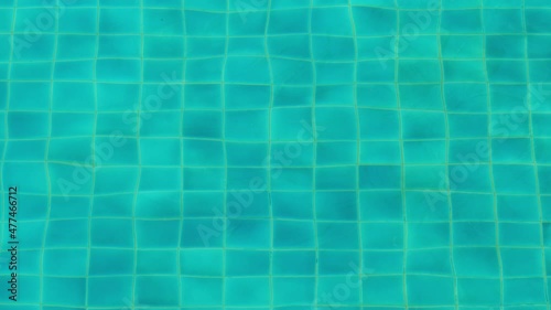 Clean water at empty pool, bottom tiles seen through waving surface. Green-blue colour from water or floor, image wobble due to refraction in small waves photo