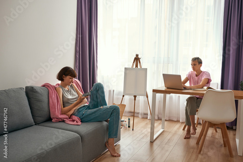 Girl use smartphone and her girlfriend use laptop © Svitlana