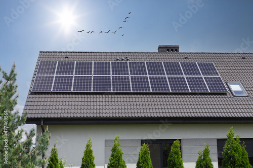 Solar panels on houseroof in front of blue sky with sun. Solar Panels On House Roof. Sustainable Renewable Energy. photo