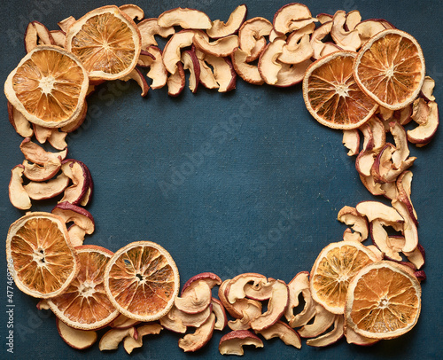 Frame of dried apple and orange slices on blue background with copy space