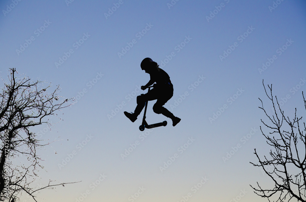 View from below strong athlete jumping in air. guy performs tricks on a scooter. concept of adrenaline View from below strong athlete jumping in air. guy performs tricks on a scooter. concept of adrenaline