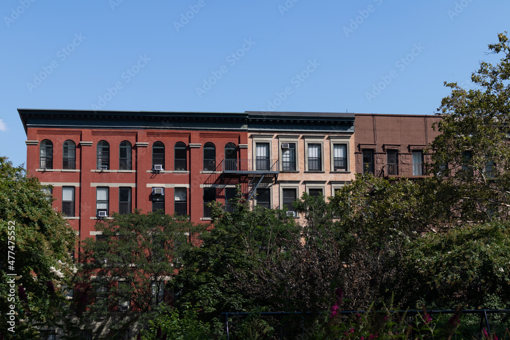 Row of Colorful Old Brick Apartment Buildings in Harlem of New York City with Green Trees