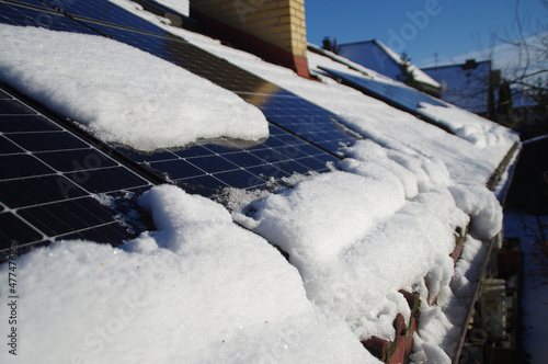 Solar PV panels covered by snow on the home roof during winter on a sunny day