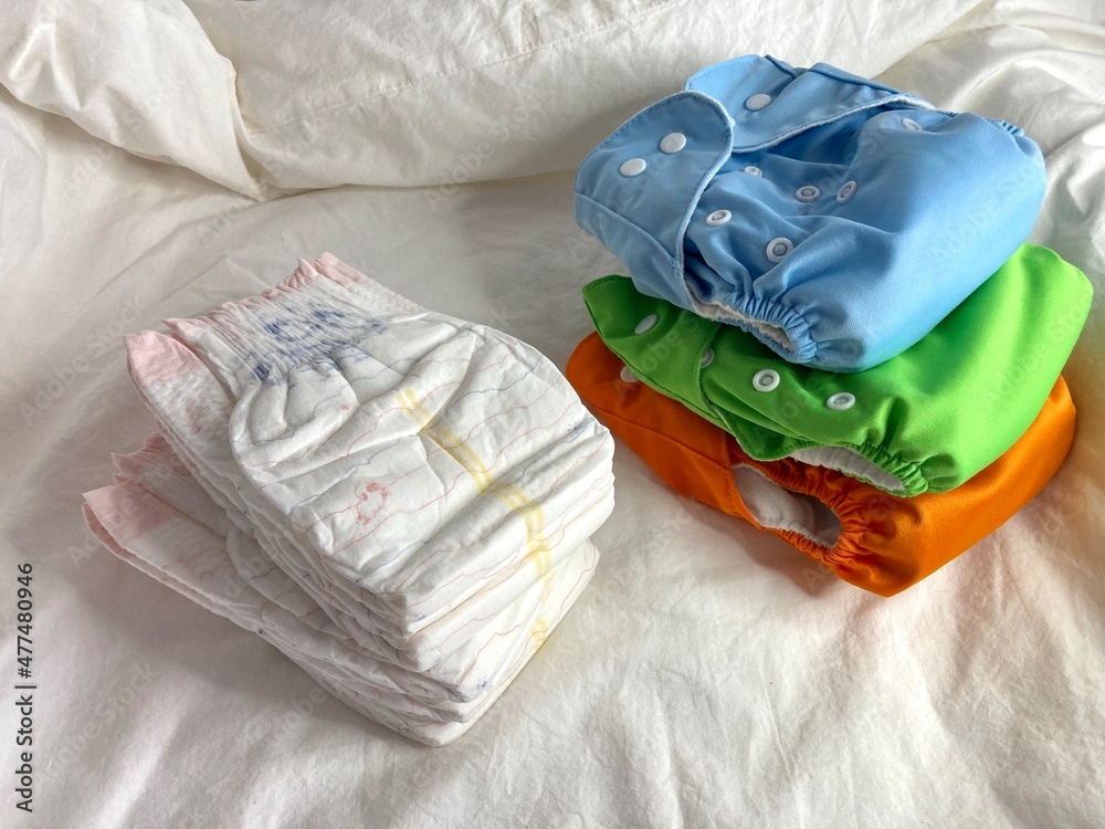 A stack of disposable diapers and a stack of reusable diapers. Taking care of the environment