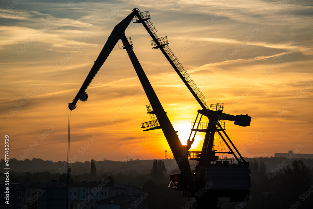 Kran an der Havel entlädt im Hafen ein Schiff im Sonnenaufgang.