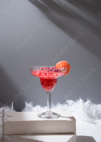 Glass of pomegranate margarita on white concrete blocks photo