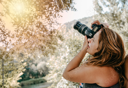 woman observes through a reflex camera to shoot in a natural environment.