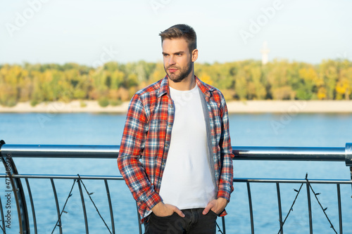 handsome unshaven man in checkered shirt outdoor, lifestyle