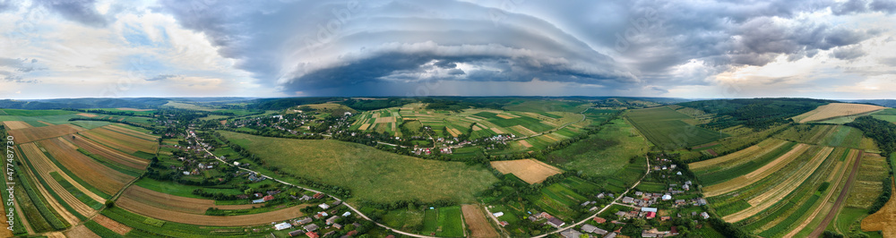 Landscape of dark clouds forming on stormy sky during thunderstorm over rural area
