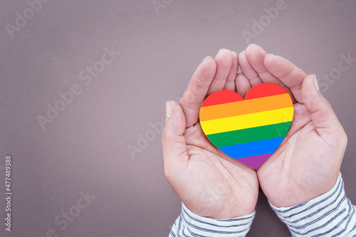 Rainbow hearts symbolize gay and LGBT pride on a human hand. Concept of human relationship, support and stay together.