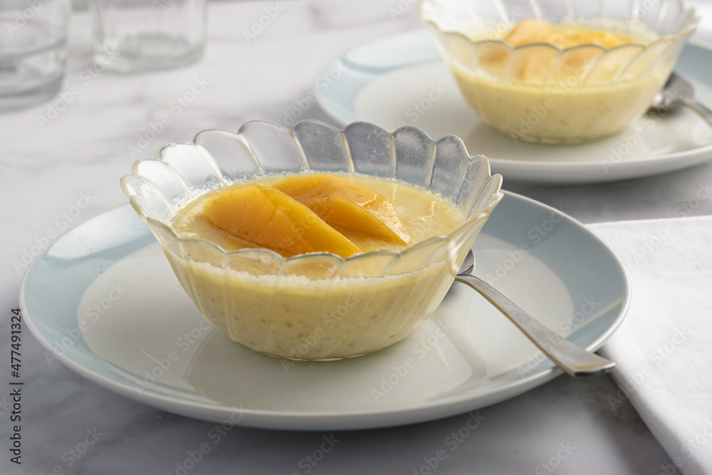 Vanilla mango pudding, caramelized sugar and mango slices. Served in a glass dessert bowl. Vanilla mango pudding, caramelized sugar and mango slices. Served in a glass dessert bowl.