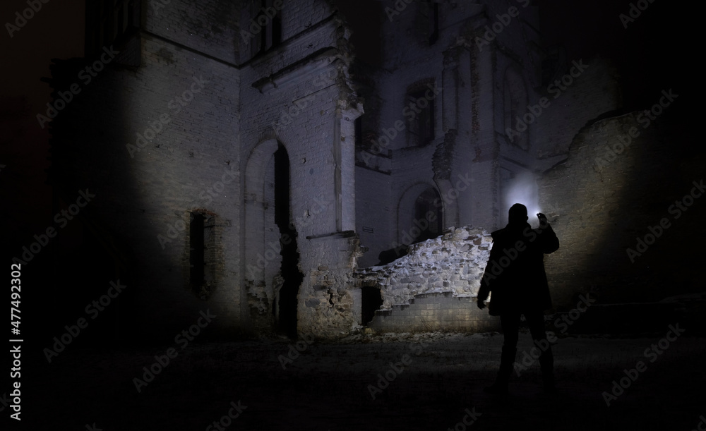 a man with a flashlight near the ruins of an old castle