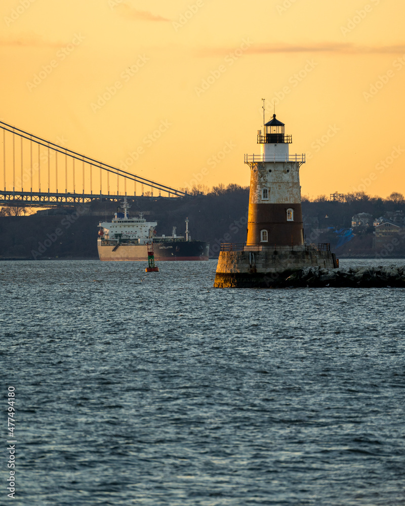 Bayonne, NJ - USA - Dec. 26, 2021: Vertical view at sunrise of the Robbins Reef Lighthouse, a sparkplug lighthouse located off Constable Hook in Bayonne, located near the Kill Van Kull, a tidal strait