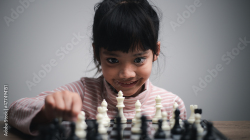 little girl playing a game of chess on a chessboard.