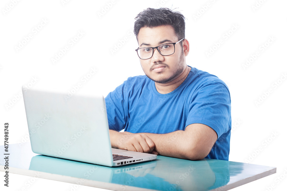 boy sitting in front of a laptop and looking towards camera boy sitting in front of a laptop and looking towards camera