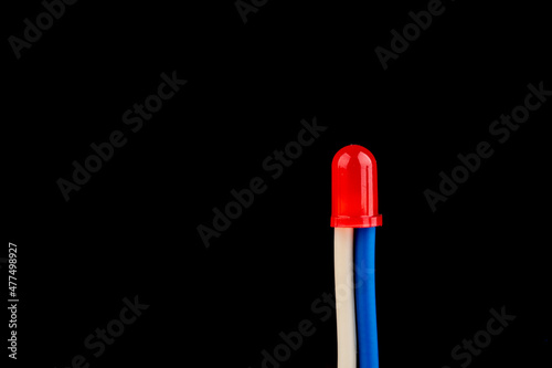Red LED with white and blue insulating tubes isolated on black background.
