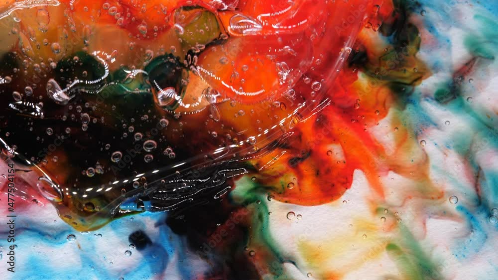 Transparent space liquid is filled with drops of red, blue, yellow and green paint.