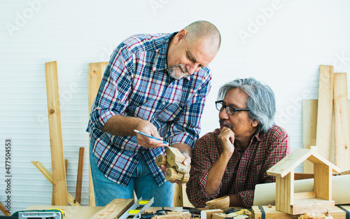 Senior old aging kind Caucasian carpenter talking to male customer, briefing plan and order, making DIY wooden furniture, smiling with happiness, sitting alone at home. Retirement, Hobby Concept.