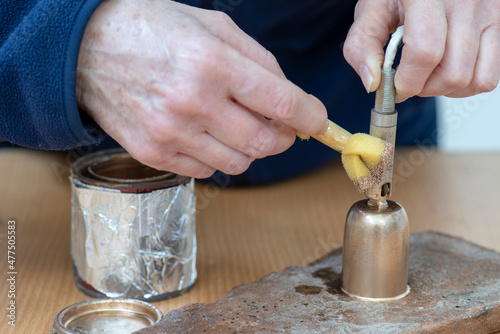 Manos restaurando un portalámparas antiguo con una esponja y pintura dorada photo