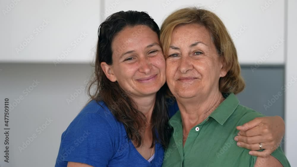 Older mother and adult daughter embracing looking at camera, family of different age generations hugging Older mother and adult daughter embracing looking at camera, family of different age generations hugging