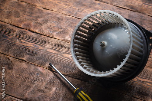 Old car fan heater motor replacement concept. Car fan heater on the wooden workbench background. photo