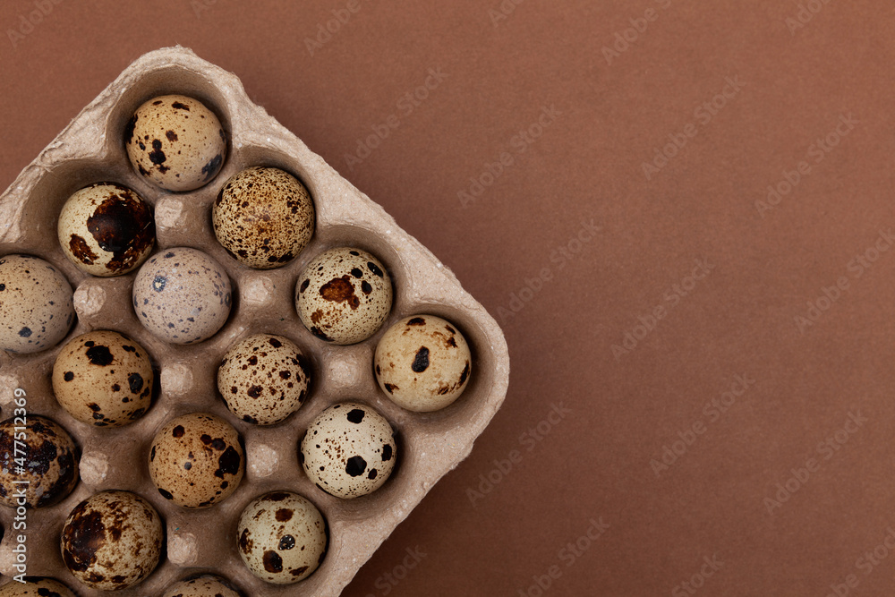 Obraz premium Quail eggs in eco package made of recycled paper, top view. Brown background, copy space