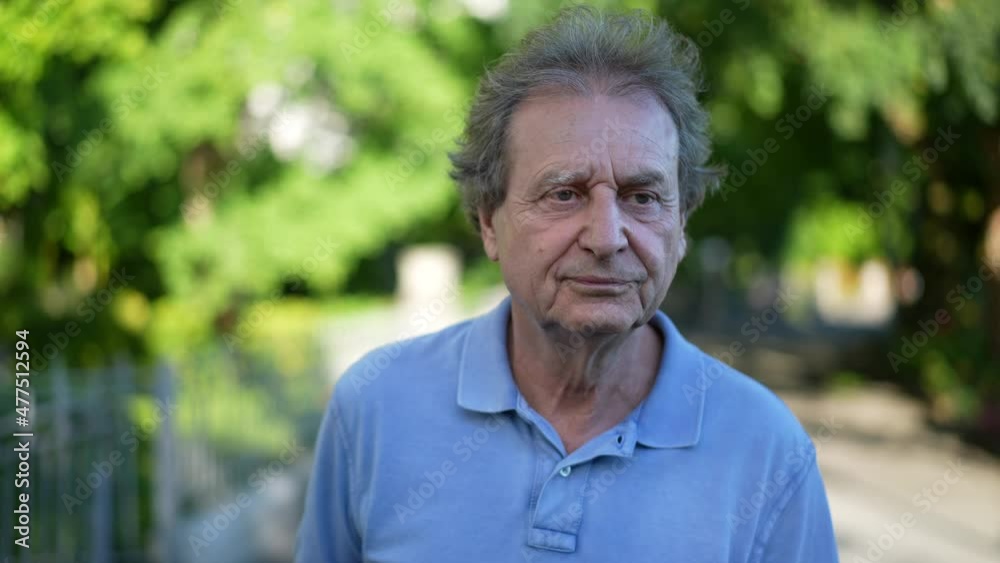One Happy senior man in 70s walking outside in green path looking at camera One Happy senior man in 70s walking outside in green path looking at camera